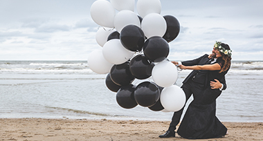 Getrouwd stel met zwarte en witte ballonnen op het strand
